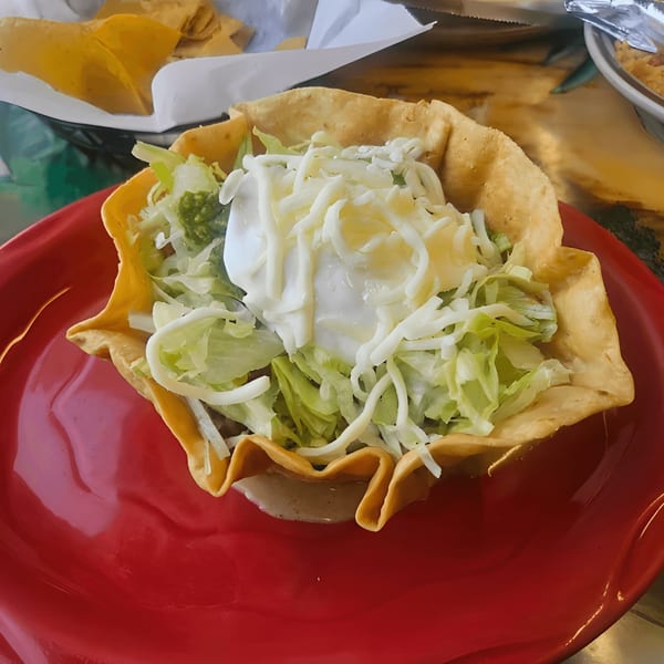 El Mezcal Grill's taco salad in a crispy tortilla bowl with lettuce, cheese, and sour cream.